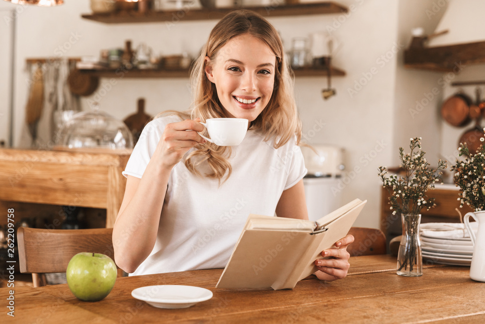 Portrait of gorgeous blond woman reading book and drinking coffee while sitting in cozy cafe indoor Portrait of gorgeous blond woman reading book and drinking coffee while sitting in cozy cafe indoor