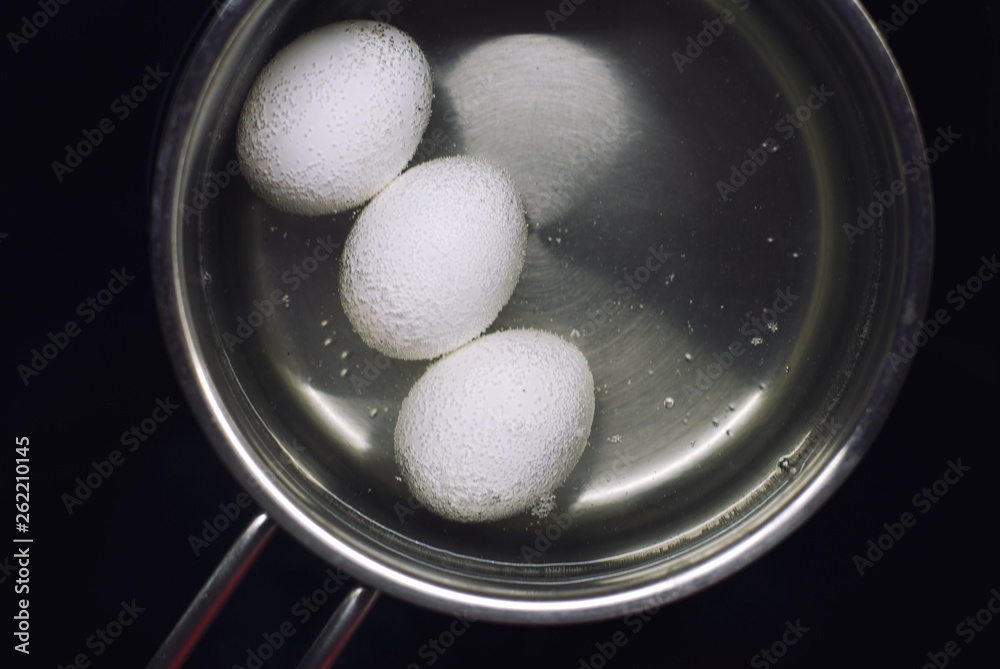chicken eggs boil in water. eggs are cooked in a saucepan on the stove. chicken eggs boil in water. eggs are cooked in a saucepan on the stove.