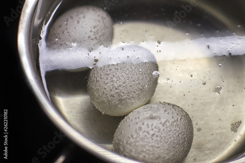 chicken eggs boil in water.  eggs are cooked in a saucepan on the stove.