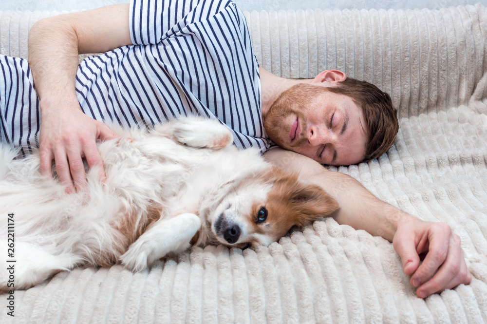 Portrait of a young man sleeping with his dog in an embrace on the bed Portrait of a young man sleeping with his dog in an embrace on the bed