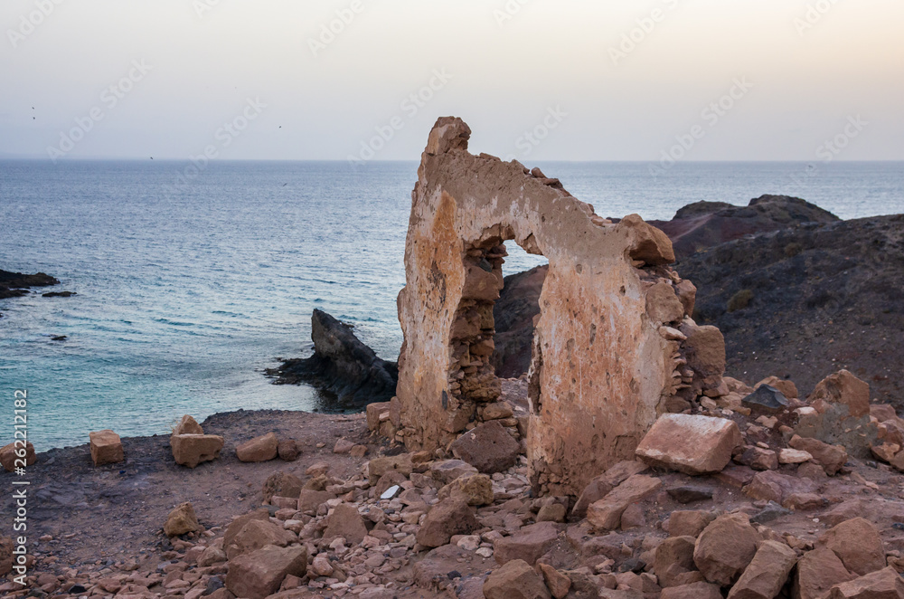 Wall with gate of a building demolished on a cliff facing the sea Wall with gate of a building demolished on a cliff facing the sea