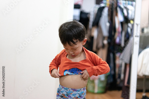 The boy tried to wear pajamas by himself.
