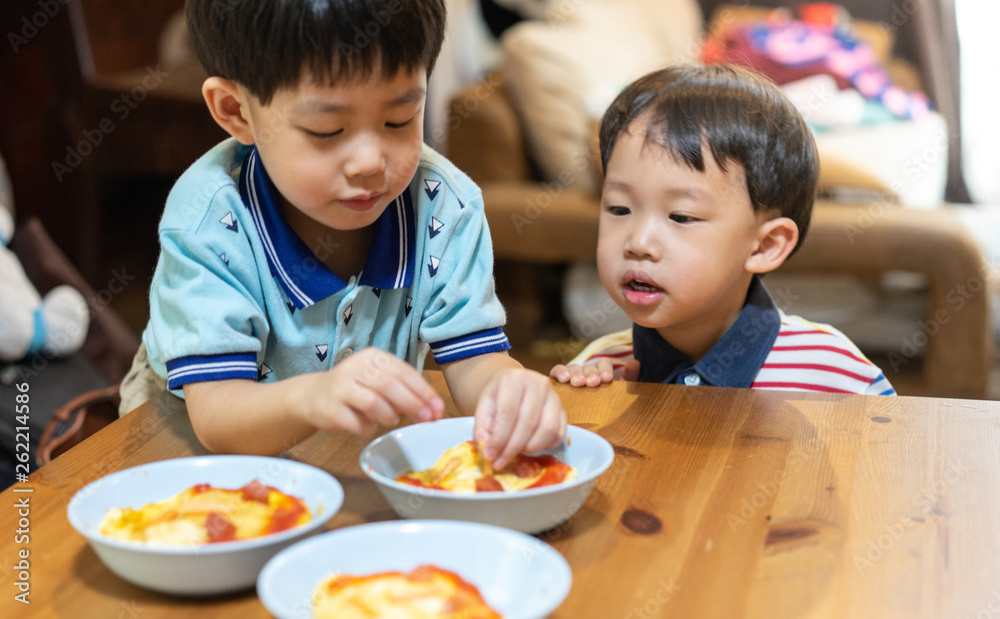 The brothers are enjoying their favorite omelet before going to school. The brothers are enjoying their favorite omelet before going to school.