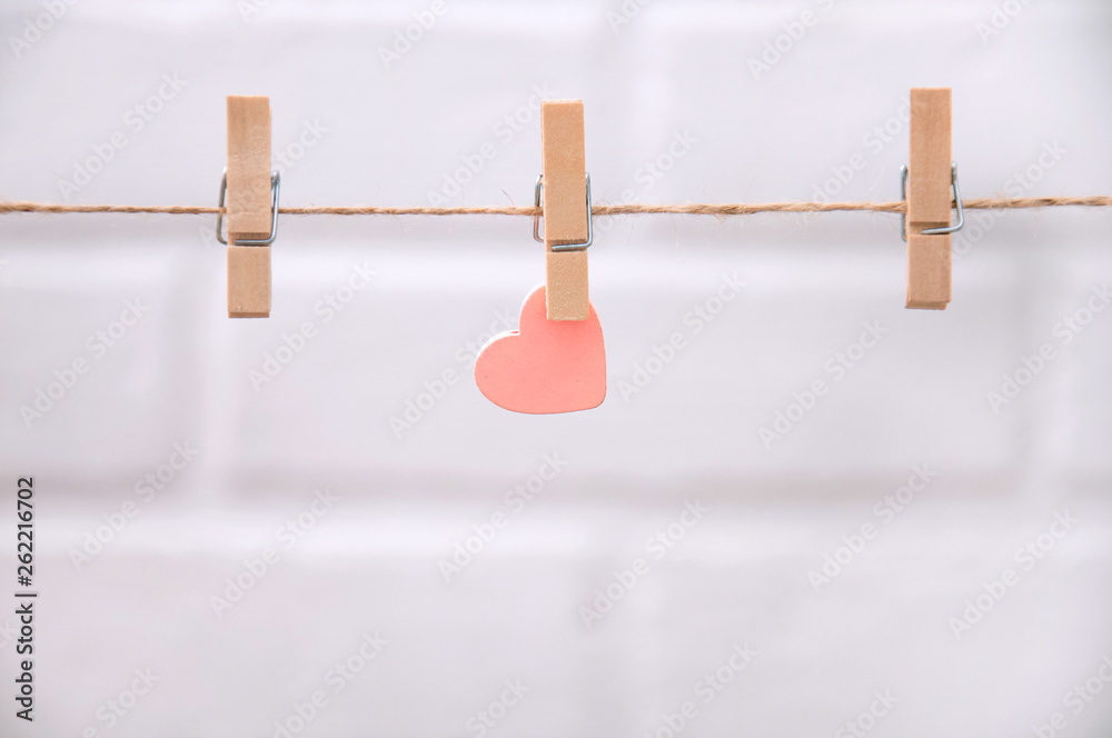 Pink heart hanging from a rope with clothespins on a white background. Greeting Card Happy Valentine's Day. Pink heart hanging from a rope with clothespins on a white background. Greeting Card Happy Valentine's Day.