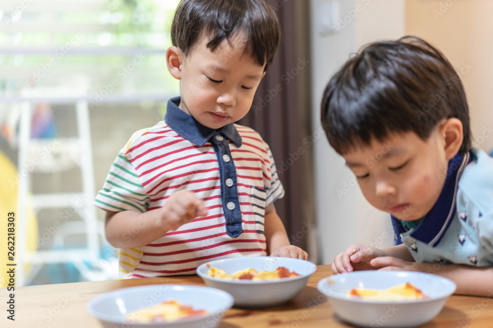 The brothers are enjoying their favorite omelet before going to school. The brothers are enjoying their favorite omelet before going to school.