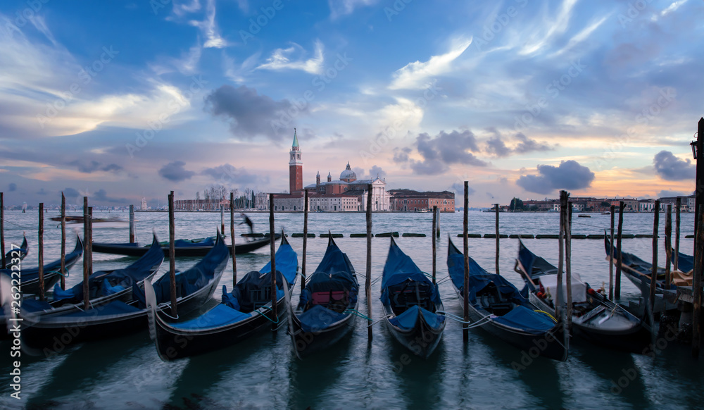 A row of gondolas parking beside the San Marco Place at sunrise with the curch San Giorgio di Maggiore in the background in Venice, Italy