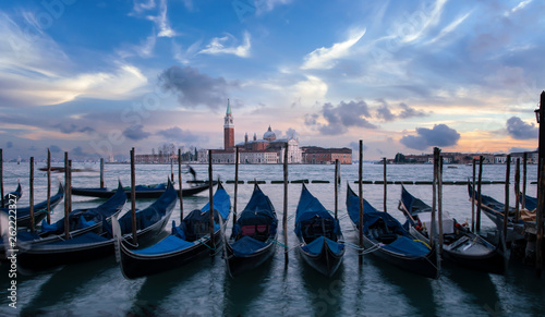 A row of gondolas parking beside the San Marco Place at sunrise with the curch San Giorgio di Maggiore in the background in Venice, Italy © Cara-Foto