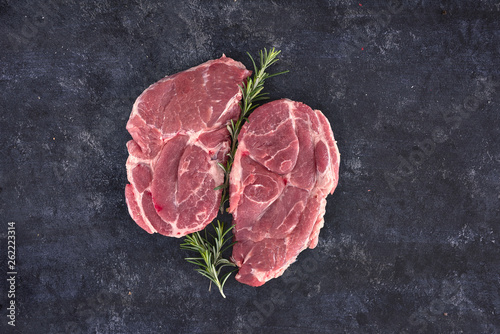 Raw meat steak on dark background. Copy space text concept. Fresh rosemary.