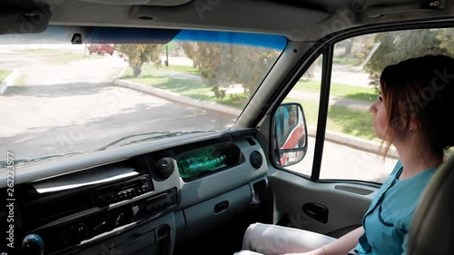A young woman, a medical professional, in an emergency ambulance car goes to the patient.