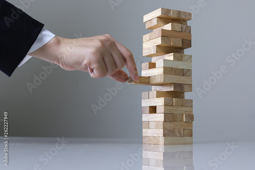 Planning, risk and strategy in business, businessman and engineer gambling placing wooden block on a tower.
