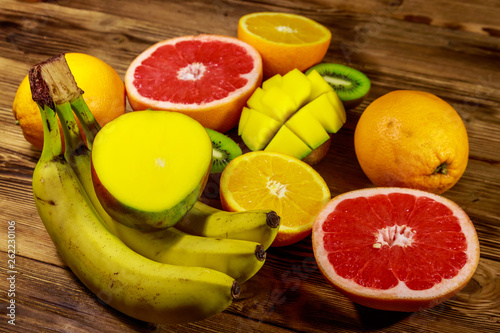 Assortment of tropical fruits on wooden table. Still life with bananas  mango  oranges  grapefruit and kiwi fruits