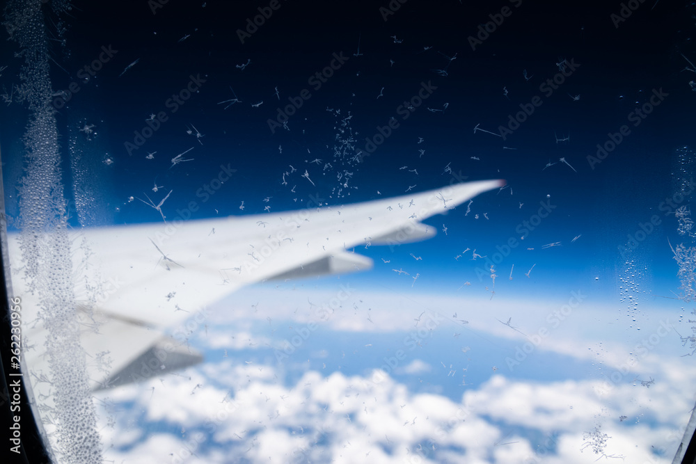 The porthole of a passenger plane covered with a layer of ice.