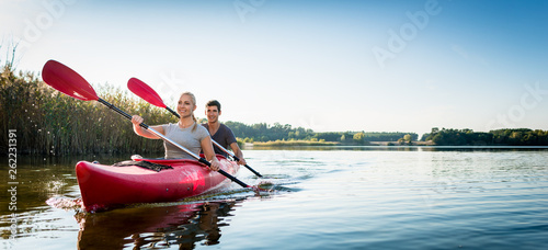 Beautiful couple sailing kayak on lake