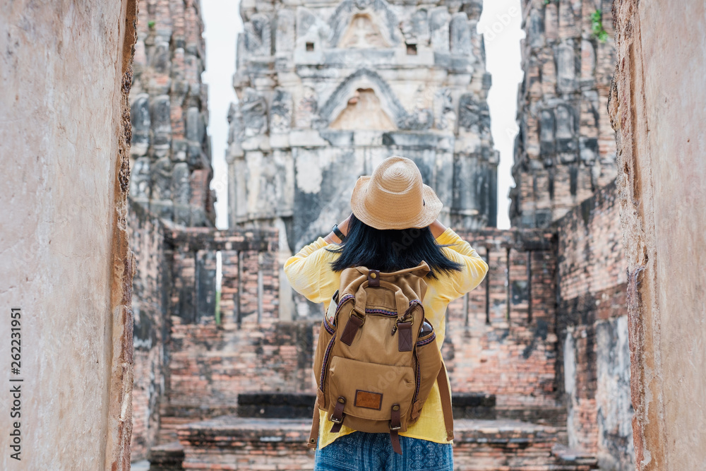 Asian tourist woman take a photo of ancient of pagoda temple thai architecture at Sukhothai,Thailand. Female traveler in casual thai cloths style visiting city concept.