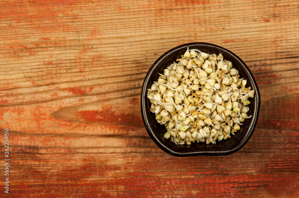 Buckwheat in a wooden bowl on an old wooden table, closeup view Buckwheat in a wooden bowl on an old wooden table, closeup view