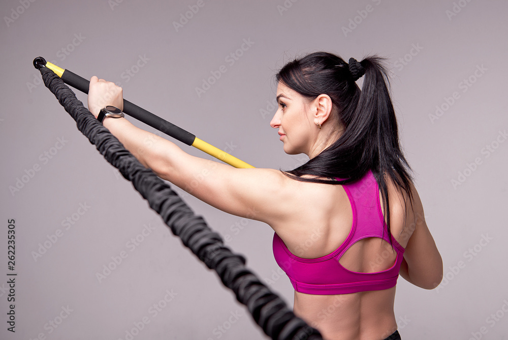 Athletic girl in a purple top and black sports leggings trains with a trainer Rip in the gym. Athletic girl in a purple top and black sports leggings trains with a trainer Rip in the gym.