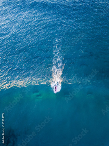 Aerial view of surfer surfs the wave.