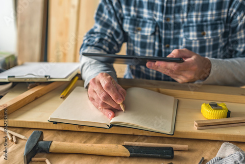 Carpenter using digital tablet to complete project to do list