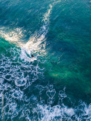 Aerial view of one surfer surfing the wave.