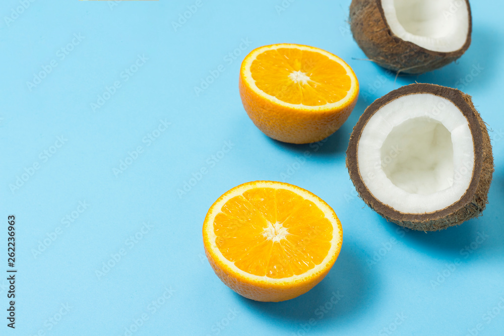 Cut orange and coconut on a blue background. Concept of tropical fruits, vacation and travel, diet and weight loss. Cut orange and coconut on a blue background. Concept of tropical fruits, vacation and travel, diet and weight loss.