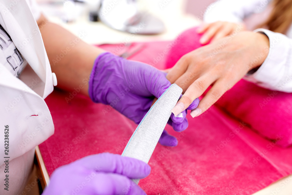 Nail treatment in a nail salon by hands of experienced manicurist