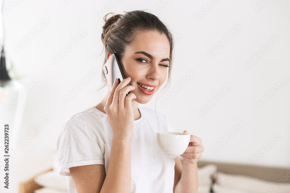 Student girl drinking coffee posing indoors talking by mobile phone. Student girl drinking coffee posing indoors talking by mobile phone.