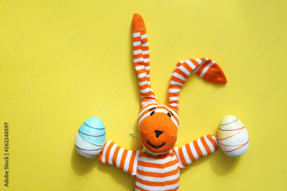 Funny Easter bunny and decorative Easter eggs on yellow background. Copy space.