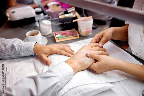 Manicurist holding a hand of a man for further treatment