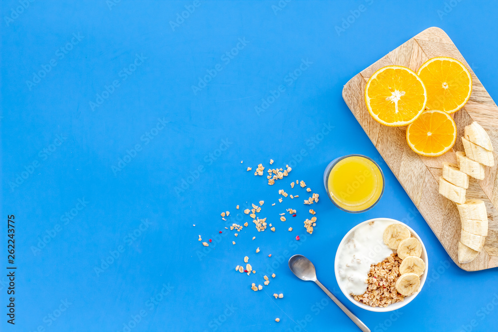 Healthy granola with banana and orange juice for colorful breakfast on blue background top view mock-up Healthy granola with banana and orange juice for colorful breakfast on blue background top view mock-up
