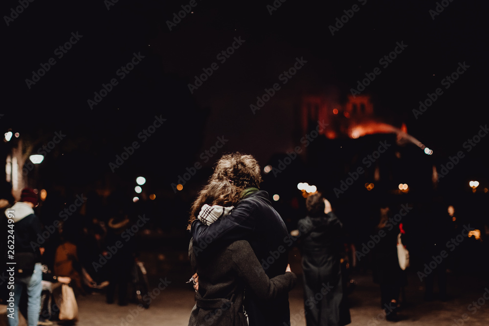 Un jeune couple triste devant la Cathédrale Notre Dame de Paris ravagée par les flammes Un jeune couple triste devant la Cathédrale Notre Dame de Paris ravagée par les flammes