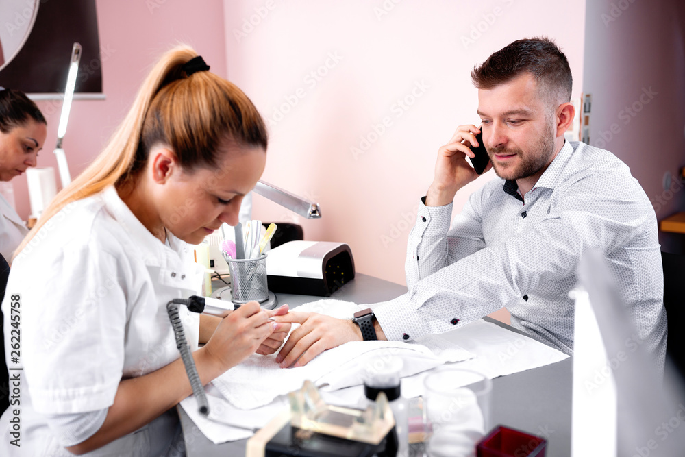 Manicurist rounding the shape of nail with electric nail machine Manicurist rounding the shape of nail with electric nail machine