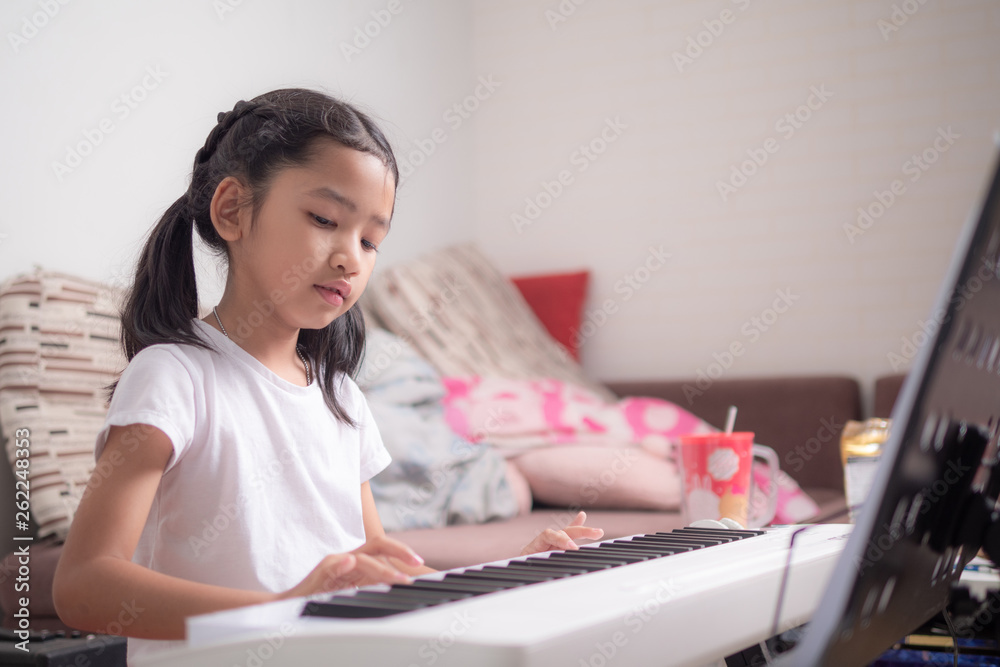 Asian little girl learning to play piano keyboard synthesizer with happiness Asian little girl learning to play piano keyboard synthesizer with happiness