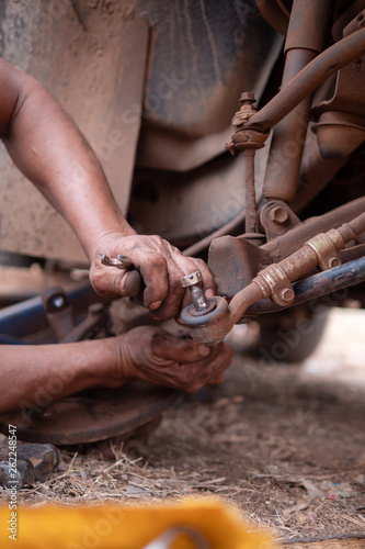 Hands of mechanic fixing wishbone control arm of the truck part to repair front wheel