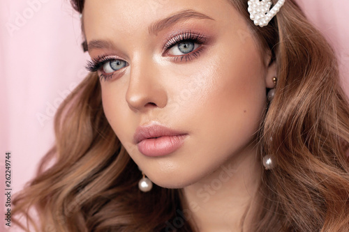 beautiful young woman with dark natural hair and tender makeup with pearl accessories