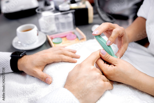 Manicurist rounding the edges using nail file