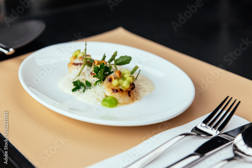 Fototapeta Naklejka Na Ścianę i Meble -  Molecular Creative Fine Dining: Hokkaido Scallop with green apple, hazelnut and shellfish veloute. Served in white plate on leather mat.