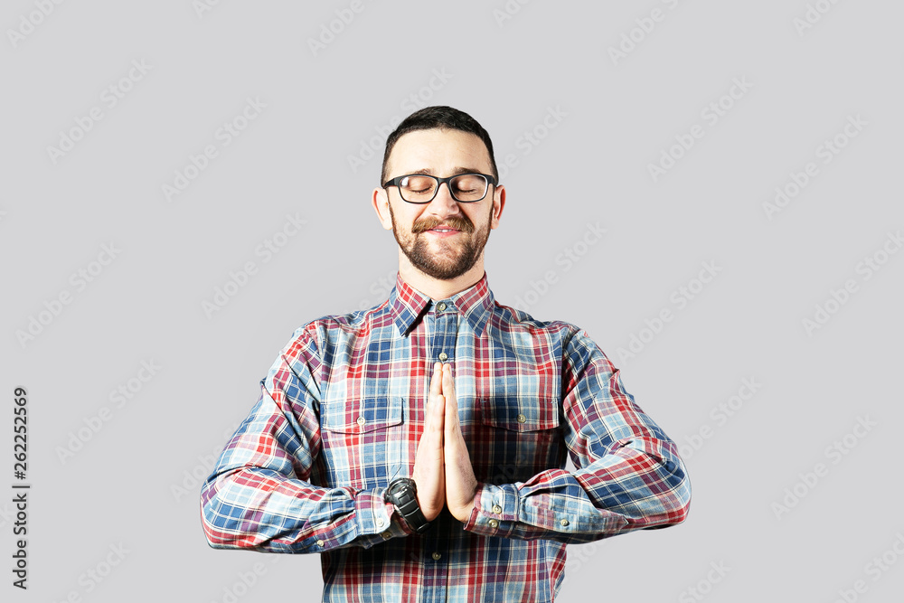 Young handsome man with facial hair posing over gray wall with a lot of copy space for text. Portrait of confident bearded male, wearing hipster slim fit checkered shirt. Isolated, background.
