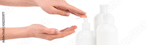 Panoramic shot of girl with cosmetic bottles applying cream isolated on white