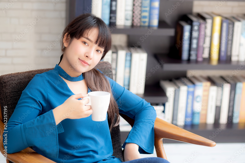 Beautiful young asian woman sitting on chair with comfort and relaxing in living room drinking a cup of coffee or tea or beverage, lifestyle asia girl leisure healthy and wellness for satisfied. Beautiful young asian woman sitting on chair with comfort and relaxing in living room drinking a cup of coffee or tea or beverage, lifestyle asia girl leisure healthy and wellness for satisfied.