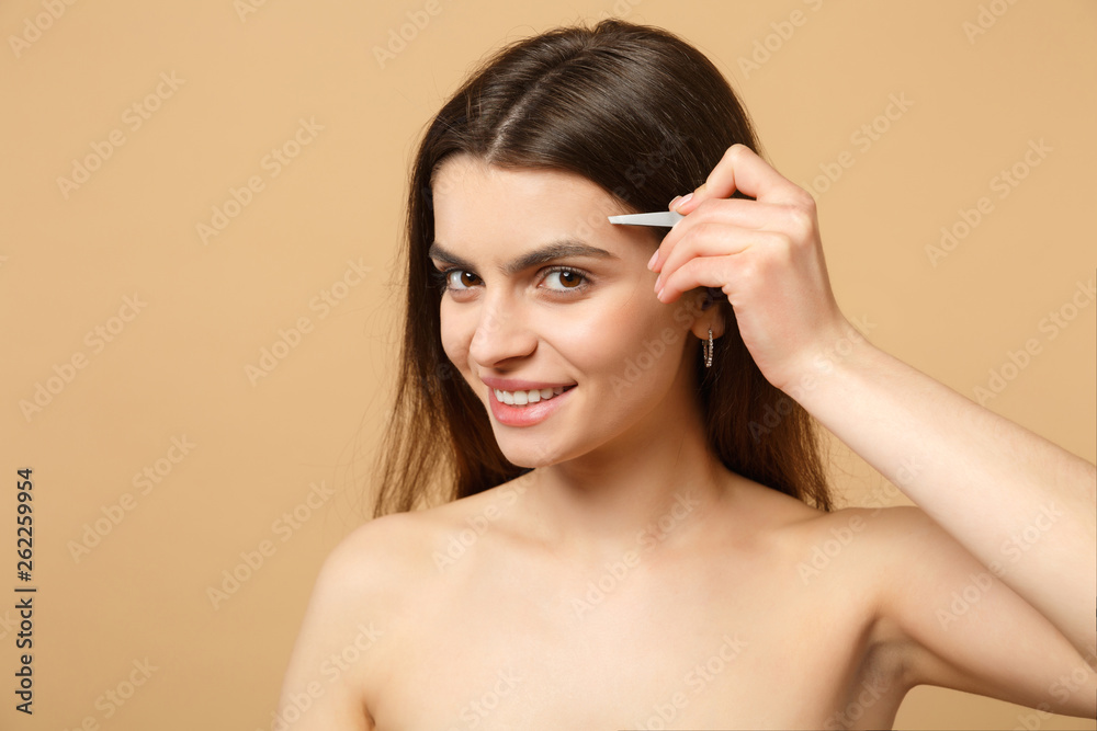 Fototapeta premium Close up brunette half naked woman 20s with perfect skin, nude make up isolated on beige pastel wall background, studio portrait. Skin care healthcare cosmetic procedures concept. Mock up copy space.