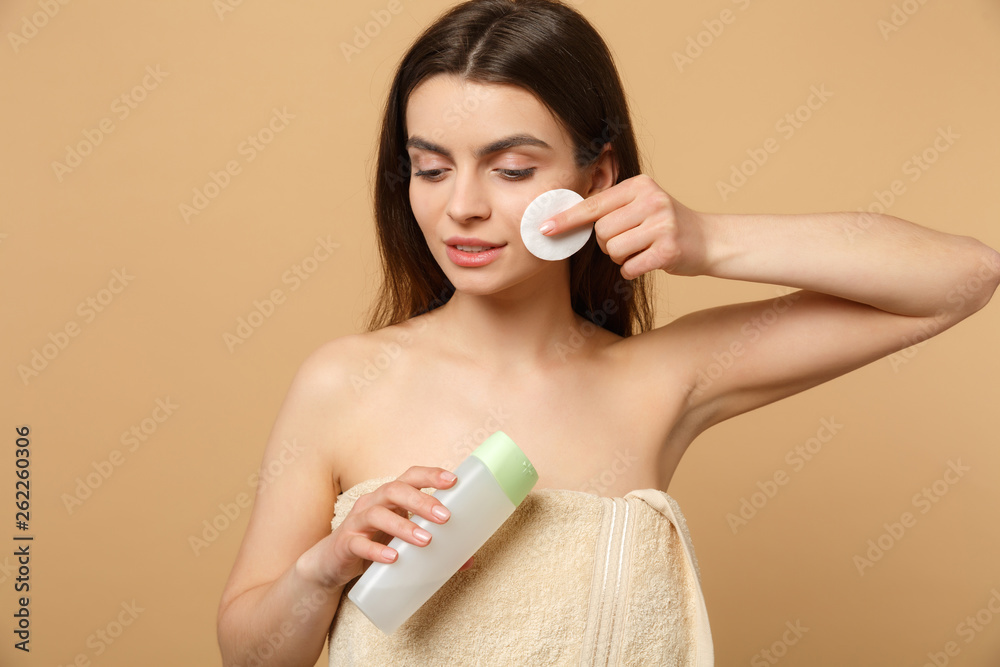 Close up brunette half naked woman 20s with perfect skin, removing nude make up isolated on beige pastel wall background, studio portrait. Health care cosmetic procedures concept. Mock up copy space. Close up brunette half naked woman 20s with perfect skin, removing nude make up isolated on beige pastel wall background, studio portrait. Health care cosmetic procedures concept. Mock up copy space.