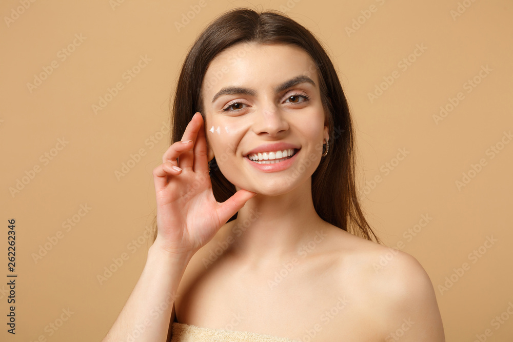 Close up half naked woman 20s with perfect skin nude make up applying facial cream isolated on beige pastel wall background, studio portrait. Healthcare cosmetic procedures concept. Mock up copy space