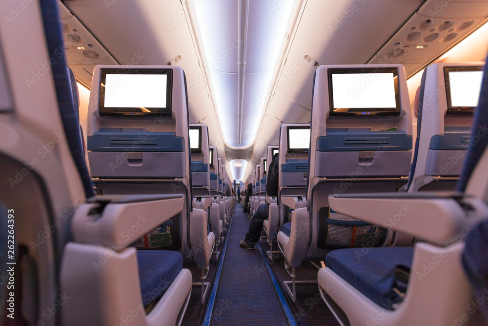Comfortable seats in cabin of aircraft with screens in chairs back Comfortable seats in cabin of aircraft with screens in chairs back