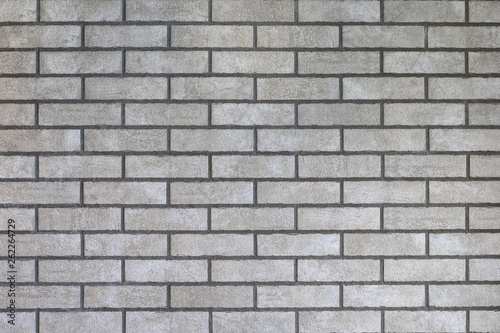 Closeup of modern neutral grey brick wall with dark seams. For pattern, texture and background