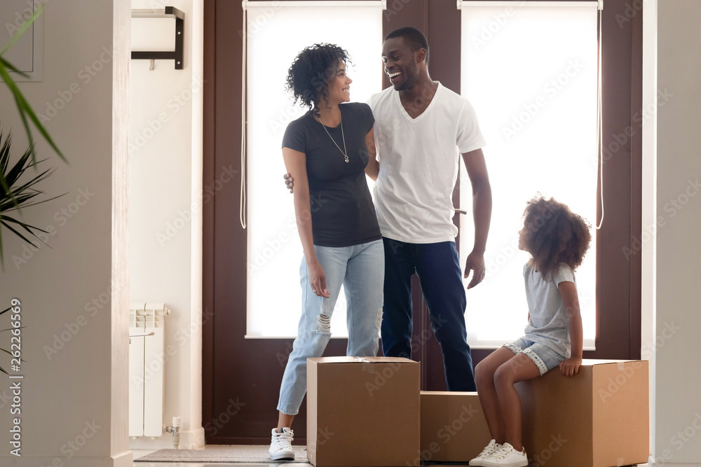 Happy African American parents standing in new house with daughter Happy African American parents standing in new house with daughter