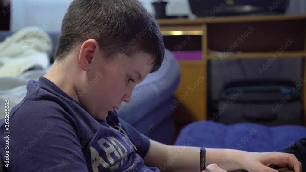 A young boy reads a book and draws. A young boy enthusiastically draws and reads a book lying on the couch. Homework. A young boy reads a book and draws. A young boy enthusiastically draws and reads a book lying on the couch. Homework.