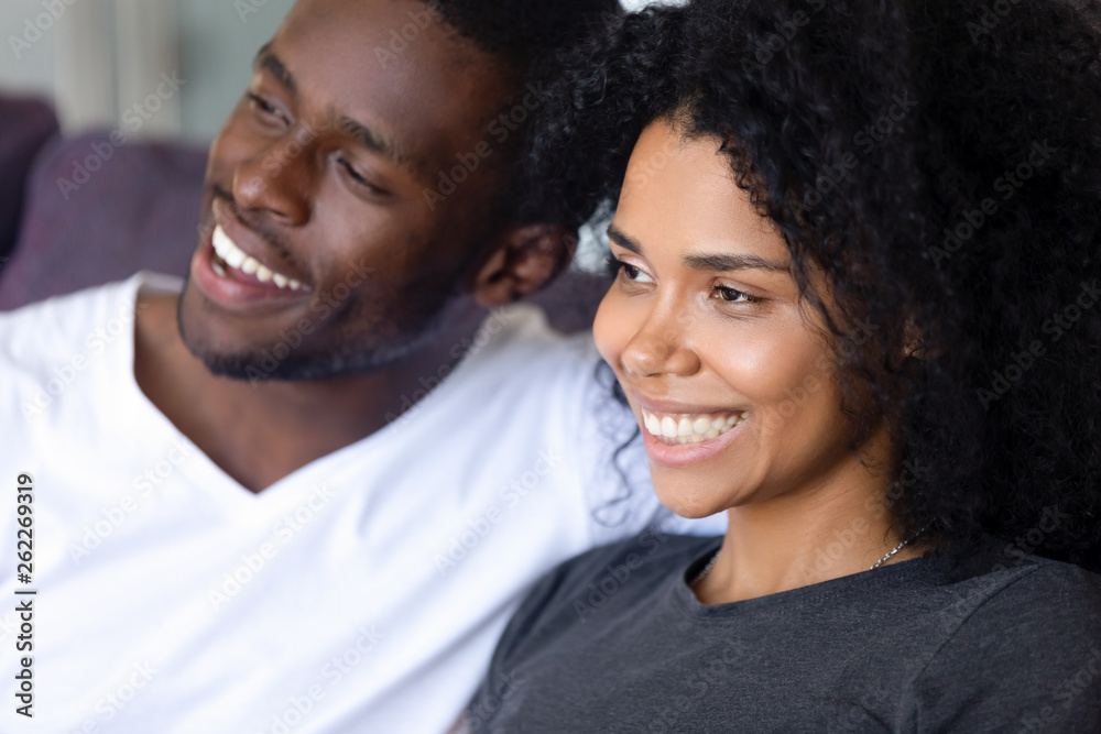 Close up happy African American couple sitting together on sofa