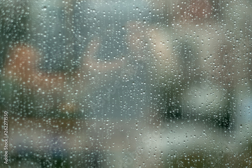 Glass window with raindrops. Overcast day and blurred cityscape outside. Symbol of sadness, depression, sorrow. Abstract texture background with copy space for text and design. Realistic image.