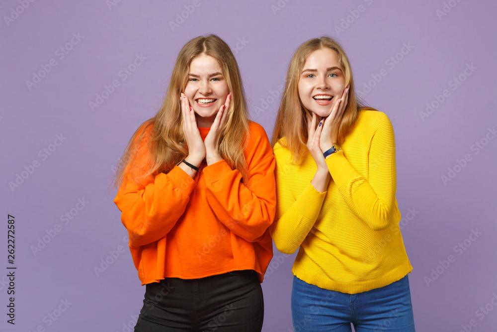 Two smiling young blonde twins sisters girls in vivid colorful c Two smiling young blonde twins sisters girls in vivid colorful c