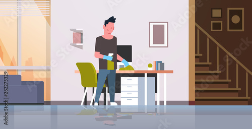 man cleaning computer table with duster guy wiping workplace desk housework concept modern living room interior male cartoon character full length horizontal
